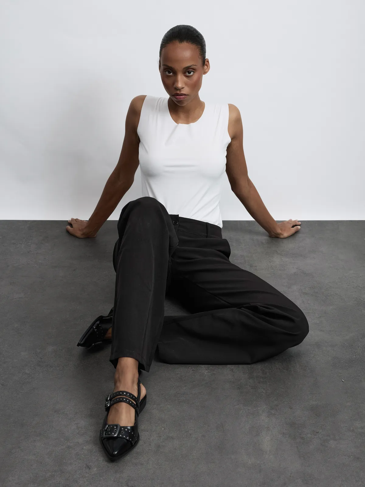 Weißes Top und schwarze Hose, sitzende Pose